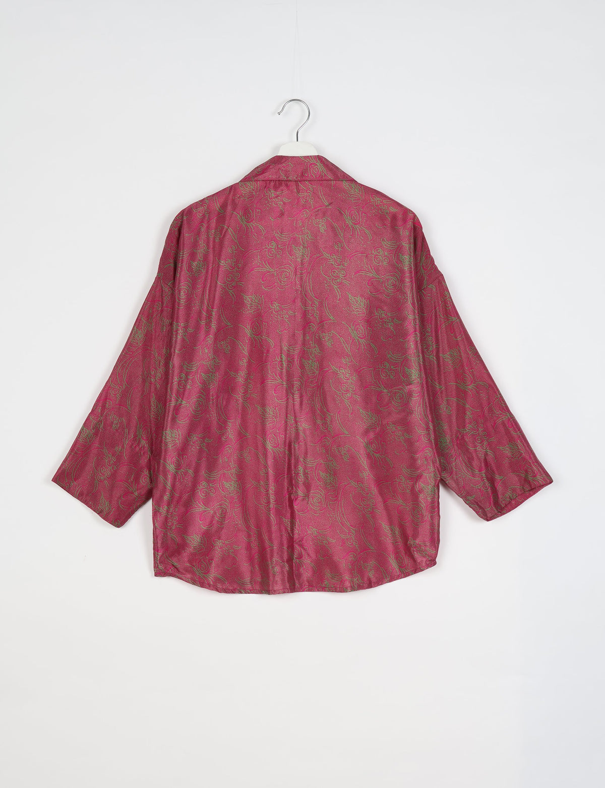 Oversized pink shirt with green tropical floral pattern, long sleeves, and spread collar, shown from back on hanger
