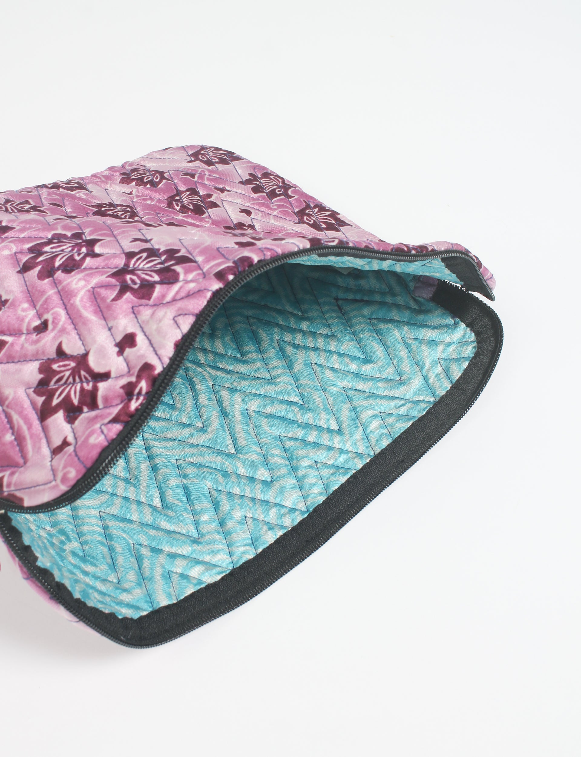 Quilted laptop sleeve with pink floral exterior and blue chevron quilted interior, partially open with black zipper visible