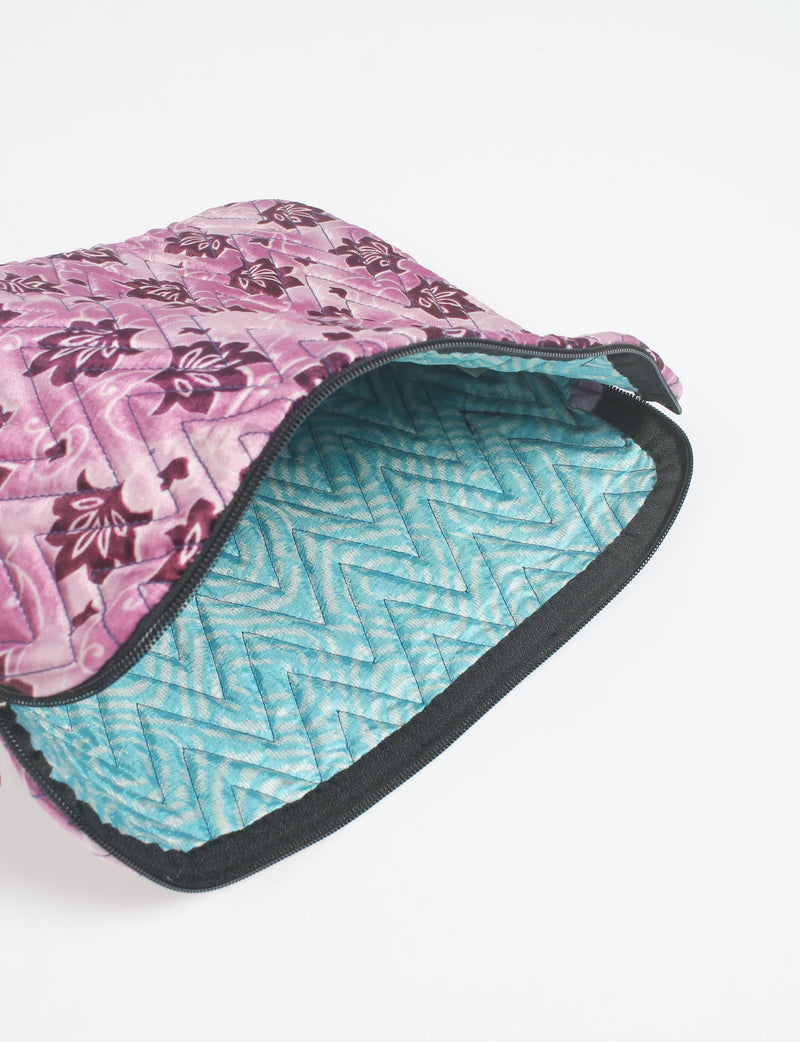 Quilted laptop sleeve with pink floral exterior and blue chevron quilted interior, partially open with black zipper visible