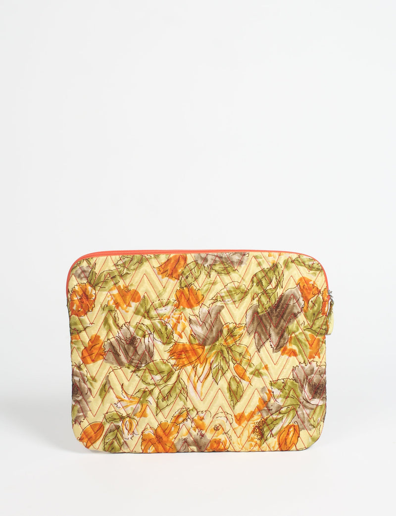 Quilted laptop sleeve with yellow floral pattern, orange zipper, and zigzag stitching, shown flat on white background