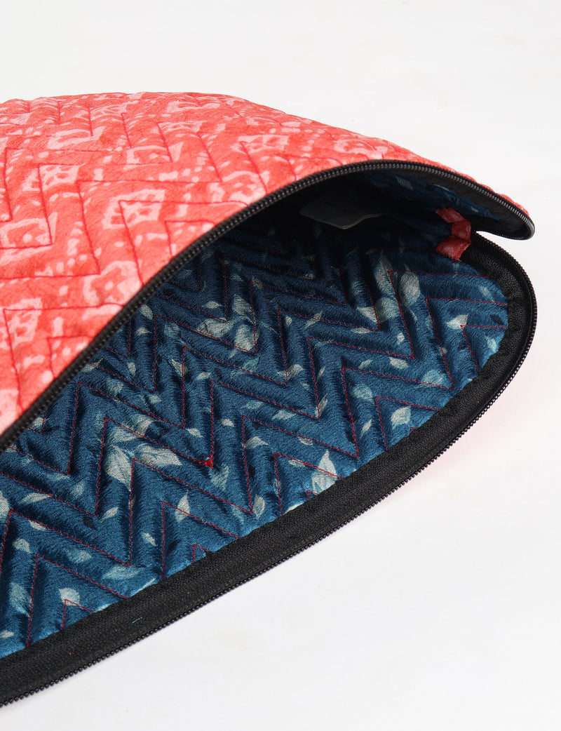 Quilted laptop sleeve with red paisley exterior and blue zigzag patterned interior, partially open with black zipper visible