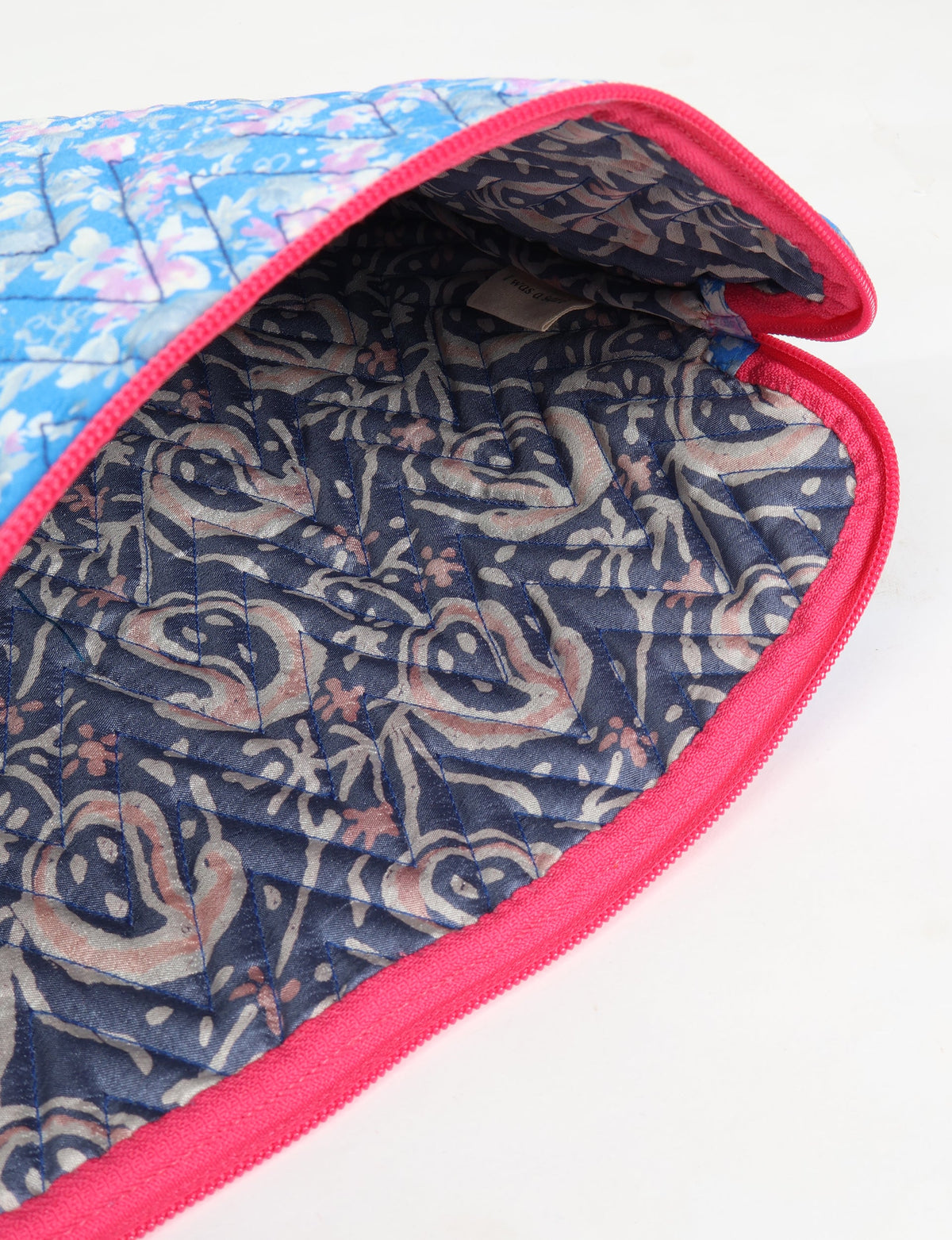 Quilted laptop sleeve with blue and pink floral exterior, red zipper trim, and dark blue paisley patterned interior lining