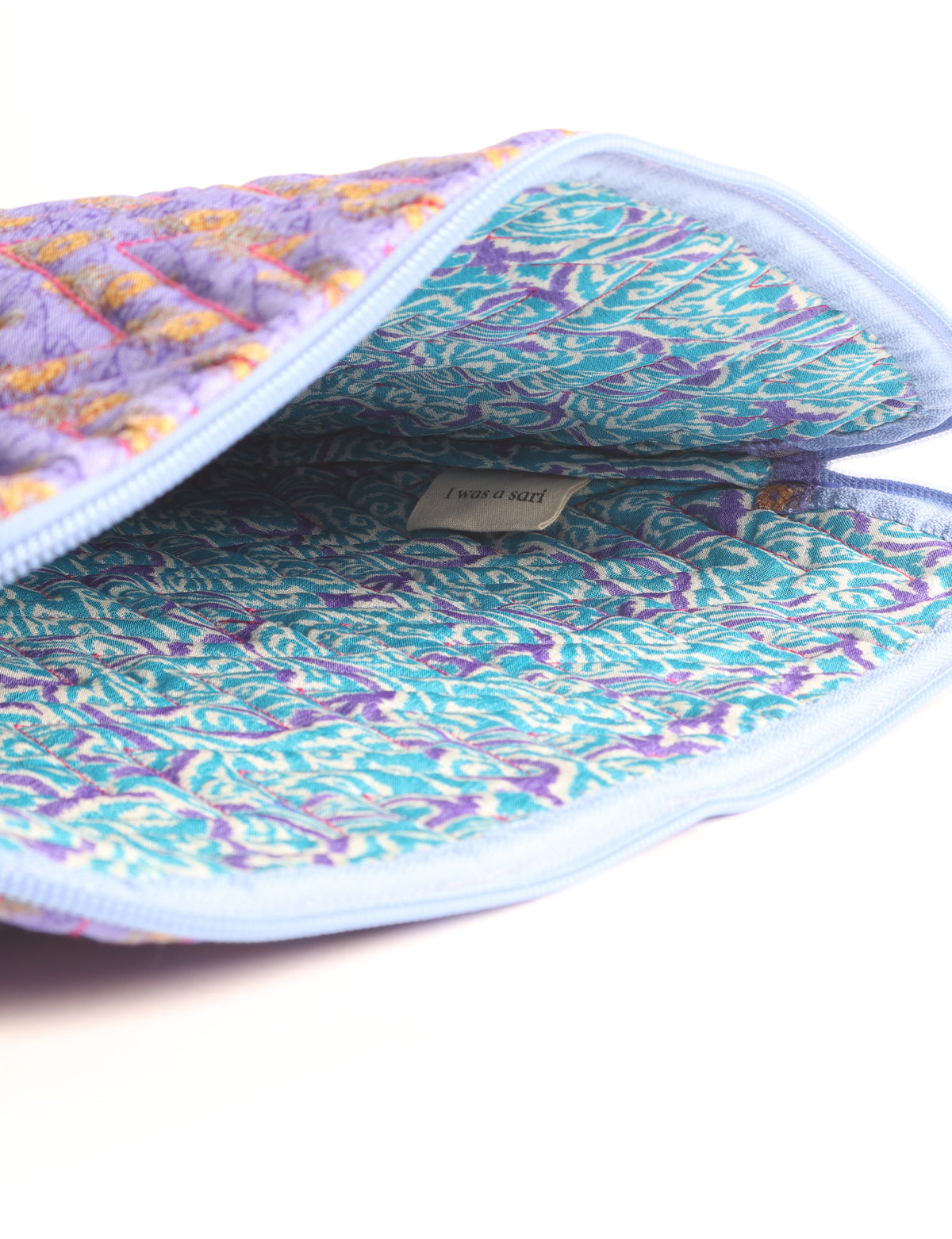 Quilted laptop sleeve with purple paisley exterior, red patterned interior, and light blue zipper, partially open showing label