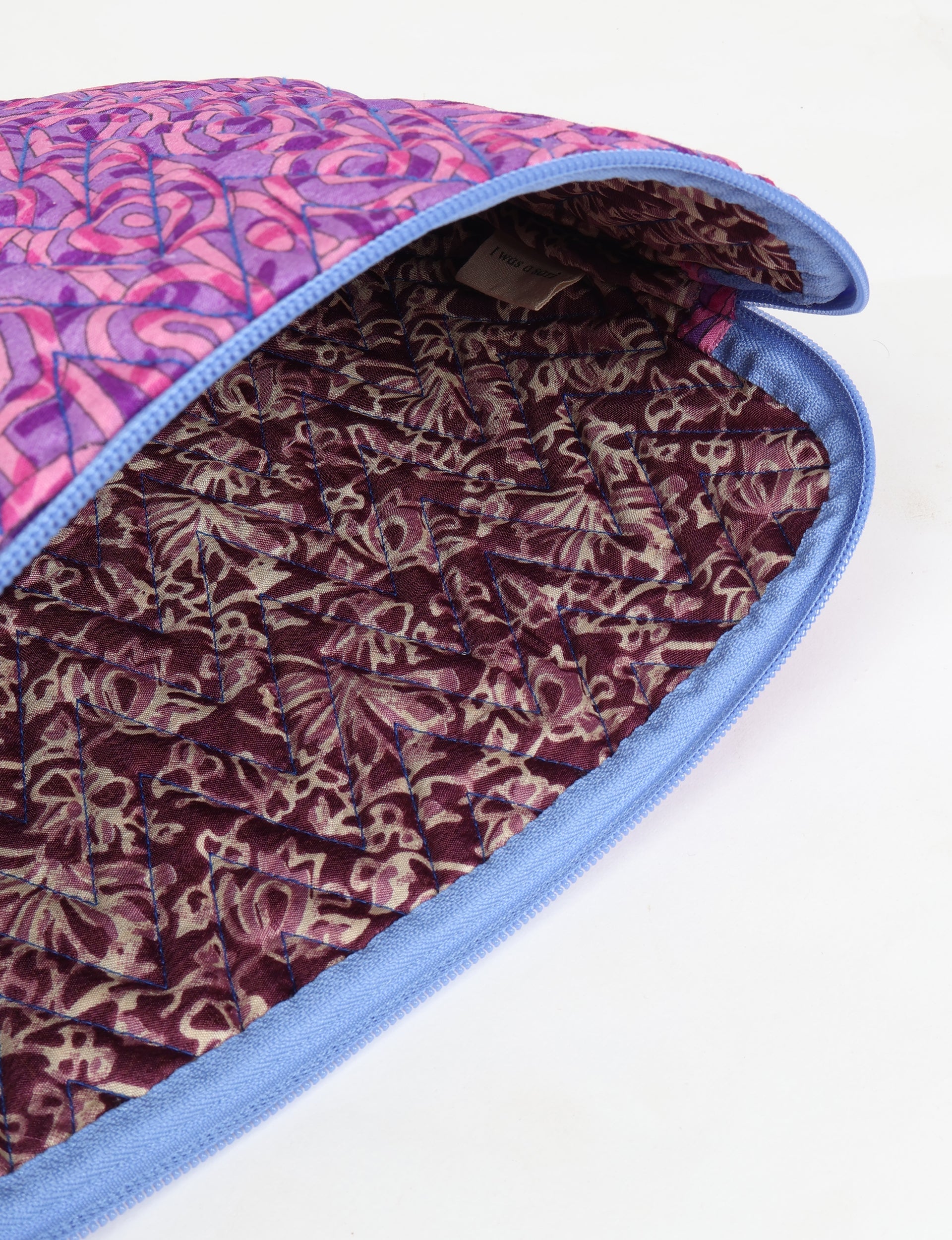 Quilted laptop sleeve with pink and purple abstract pattern, blue zipper, and brown patterned interior lining, open view
