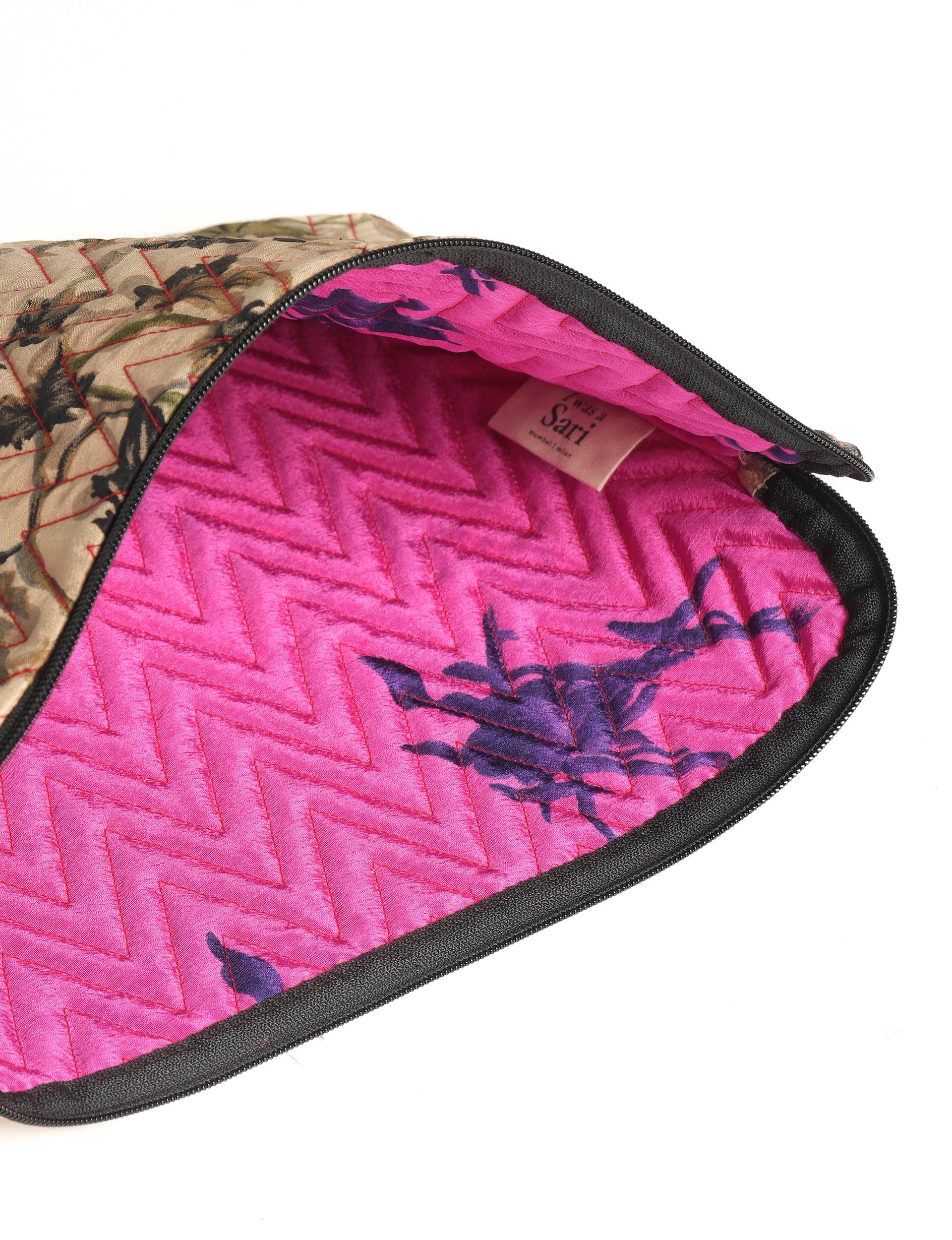 Quilted beige floral laptop sleeve with pink quilted interior and black zipper, partially open showing label inside