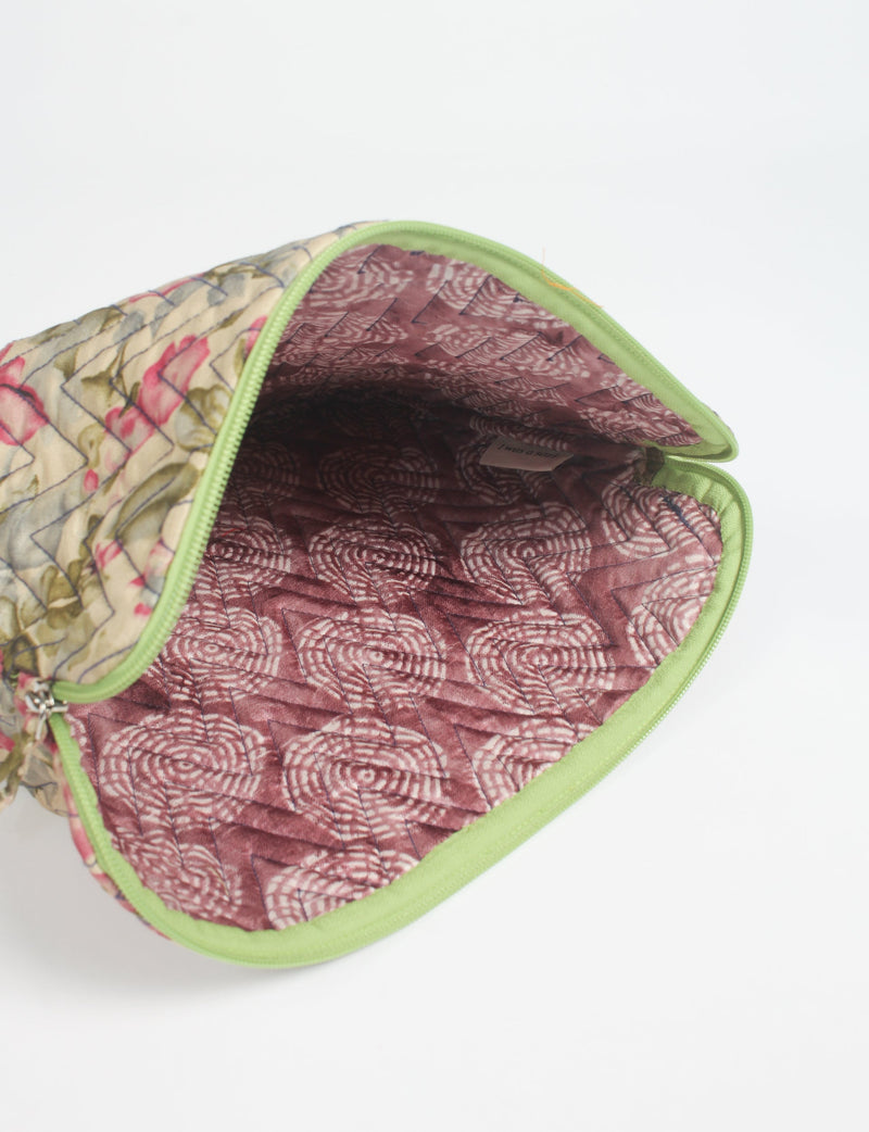 Quilted laptop sleeve with beige floral exterior, green zipper, and maroon patterned interior, shown open from top angle