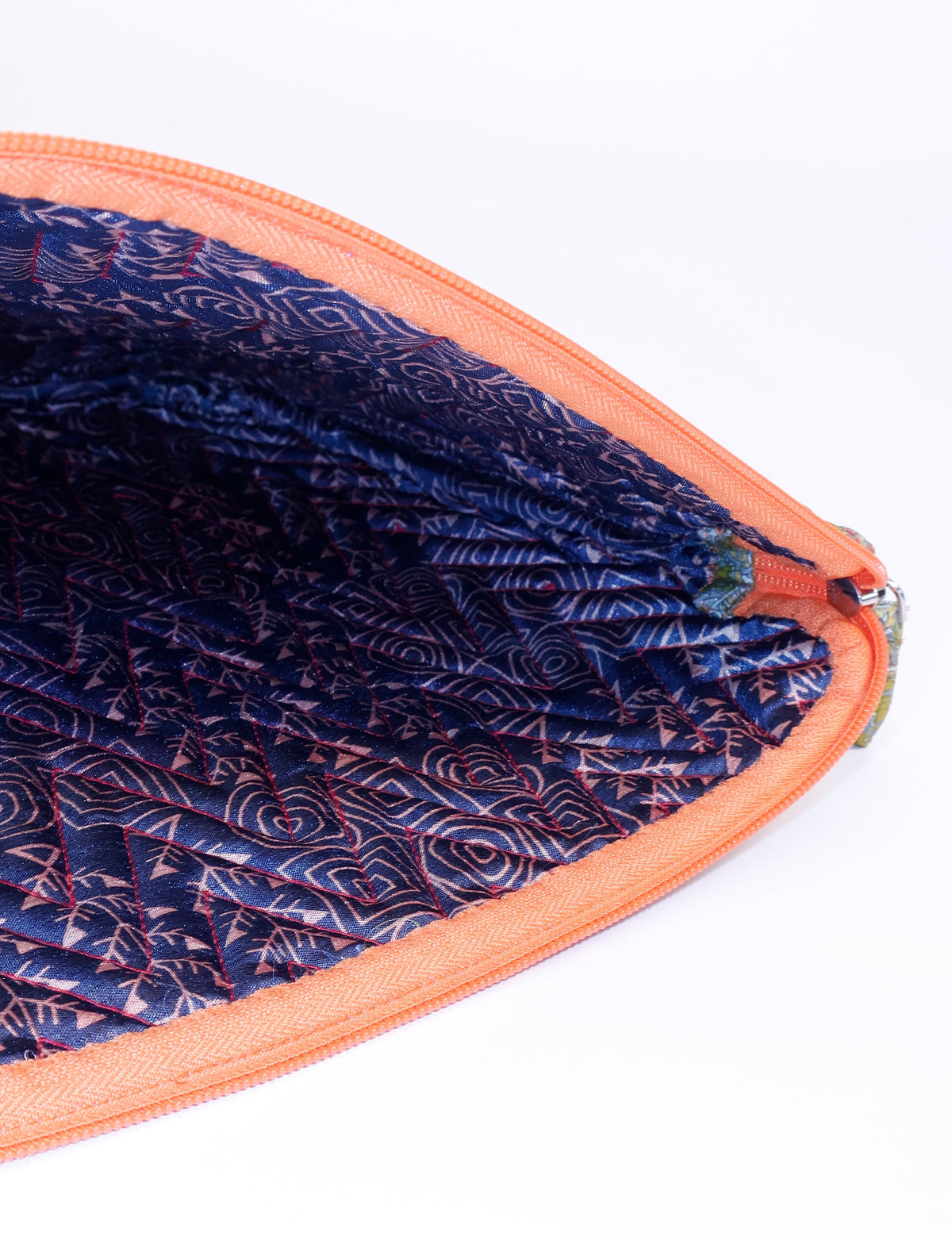 Quilted laptop sleeve with orange zipper and blue patterned fabric interior, shown in close-up view