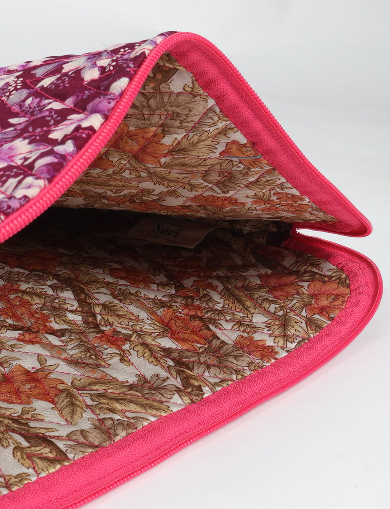 Quilted laptop sleeve with pink floral exterior, pink zipper, and brown floral patterned interior, open flat