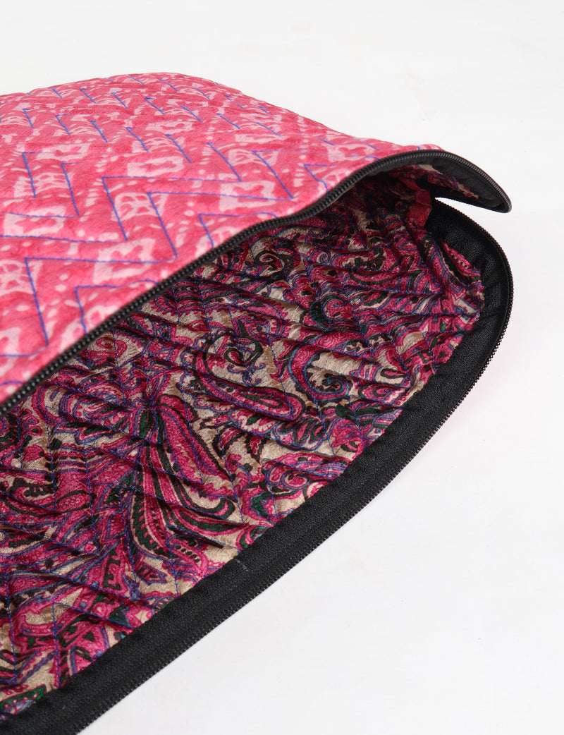 Quilted pink geometric laptop sleeve with zipper, showing patterned fabric interior and black trim edge