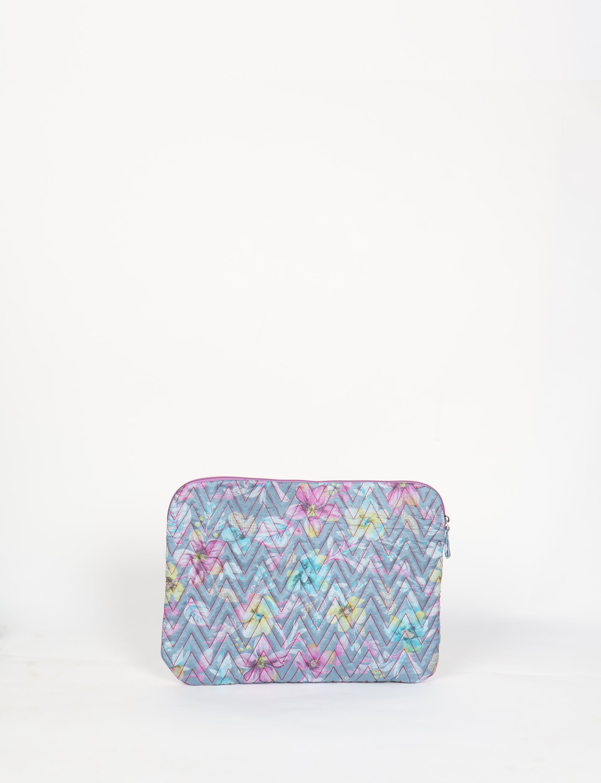 Quilted laptop sleeve with grey floral pattern, pink zigzag stitching, and zipper closure, shown front view on white background