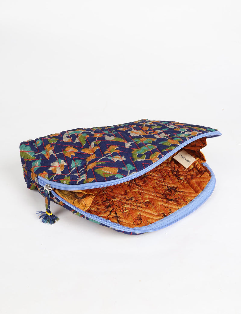 Blue tropical quilted cotton vanity pouch with zipper, partially open showing orange floral interior and label
