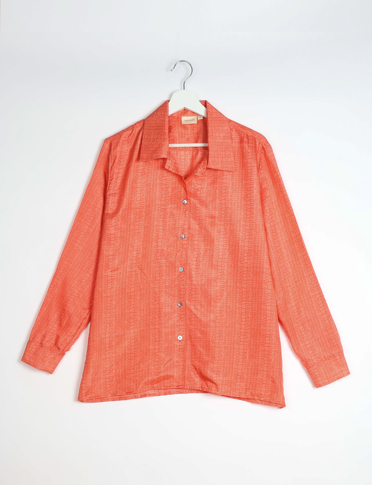 Orange resort shirt with abstract pattern, long sleeves, button front, and spread collar, hanging on white hanger