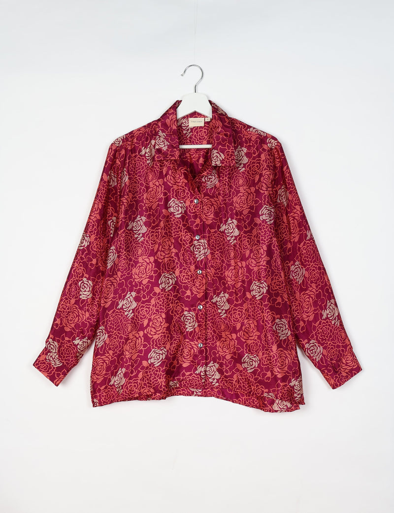 Long-sleeve pink floral resort shirt with button front and collar, hanging on white hanger against white background