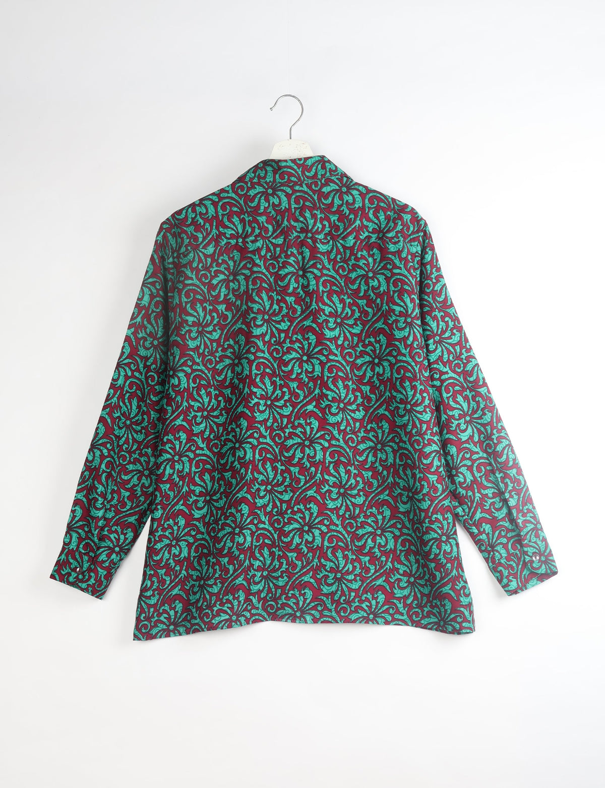 Long-sleeve resort shirt with red and teal leaf swirl pattern, shown from back on white hanger against white background