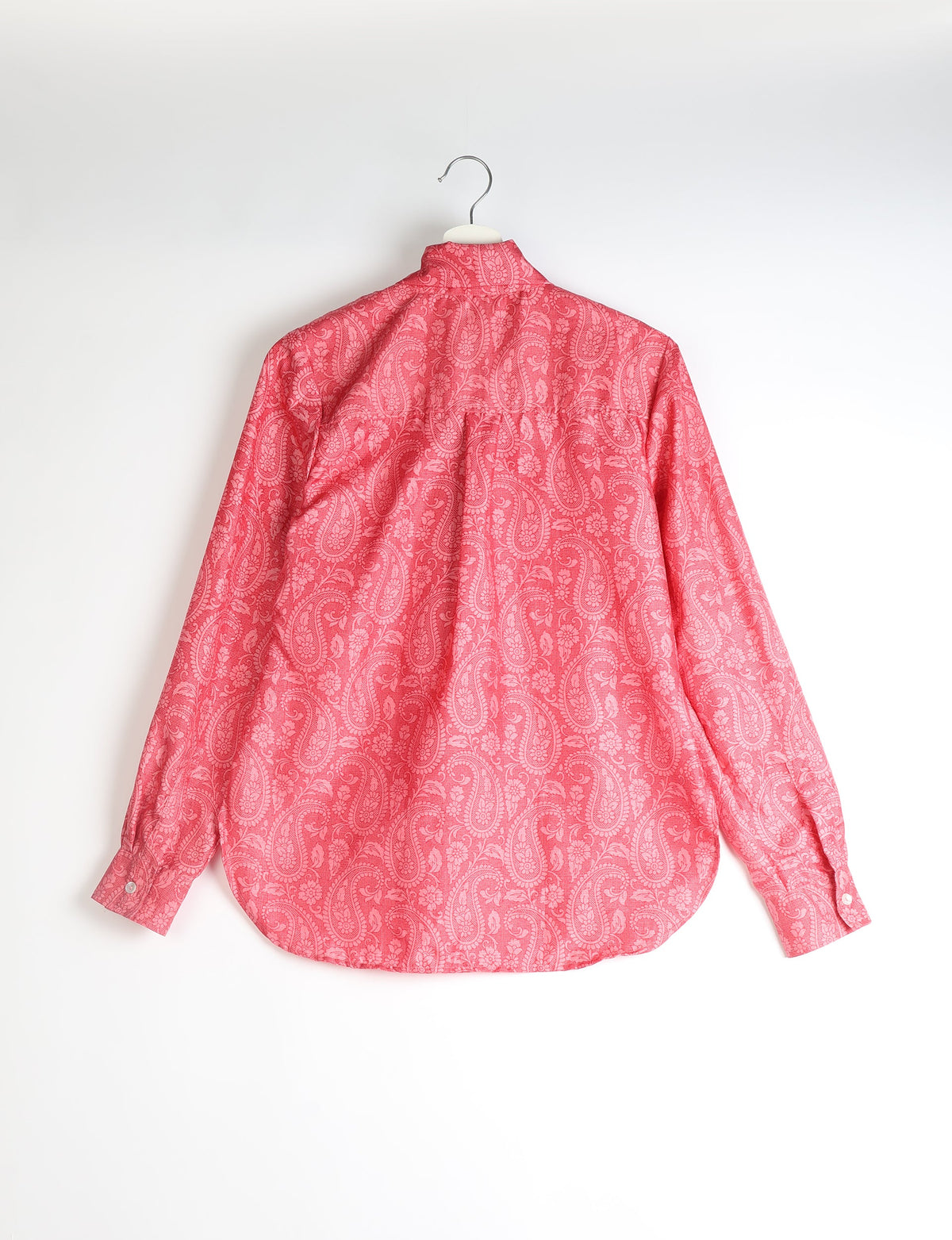 Pink paisley patterned long-sleeve shirt hanging, showing back view with buttoned cuffs and curved hem