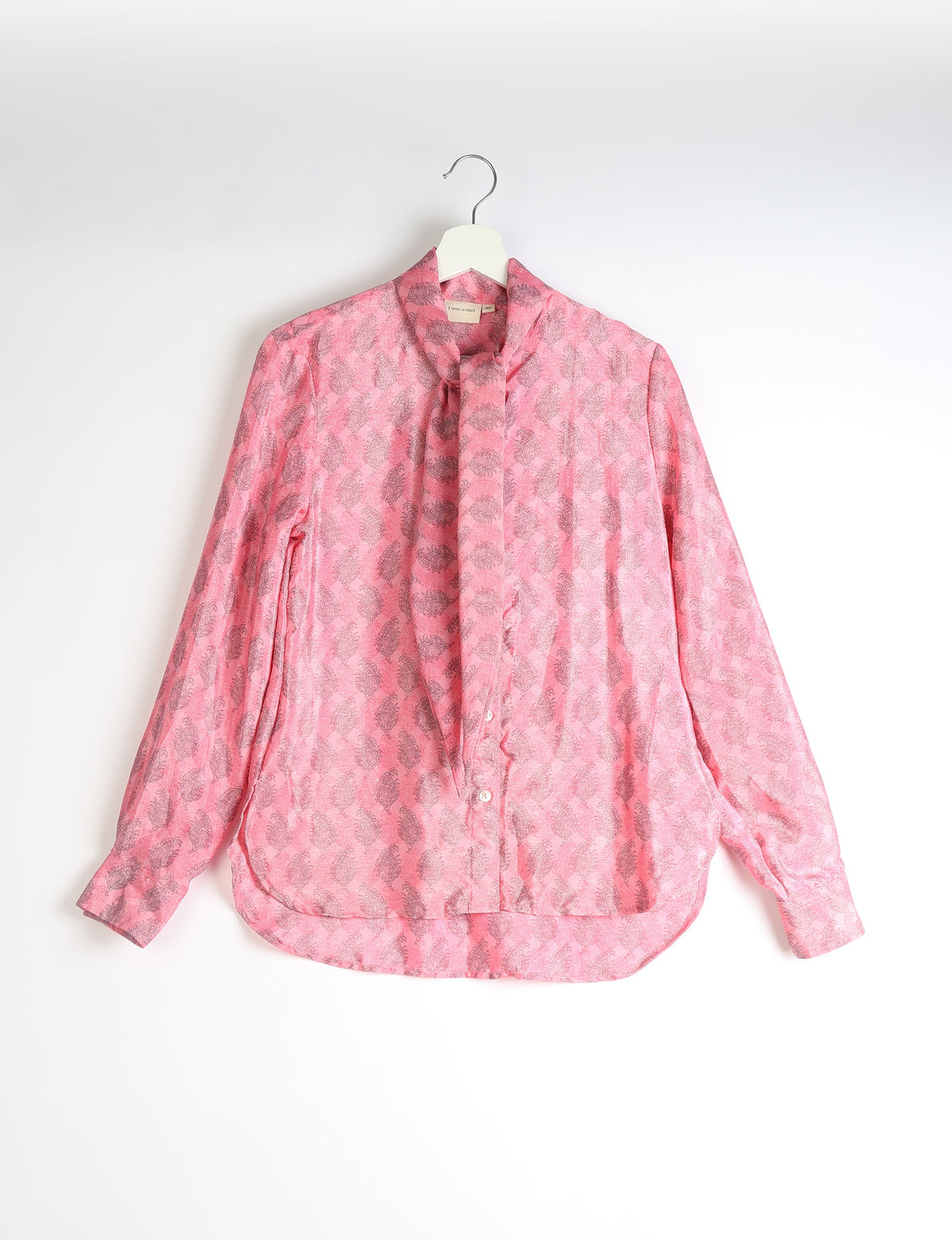 Pink long-sleeve button-up shirt with bowtie collar and gray leaf pattern, hanging on white hanger against white background