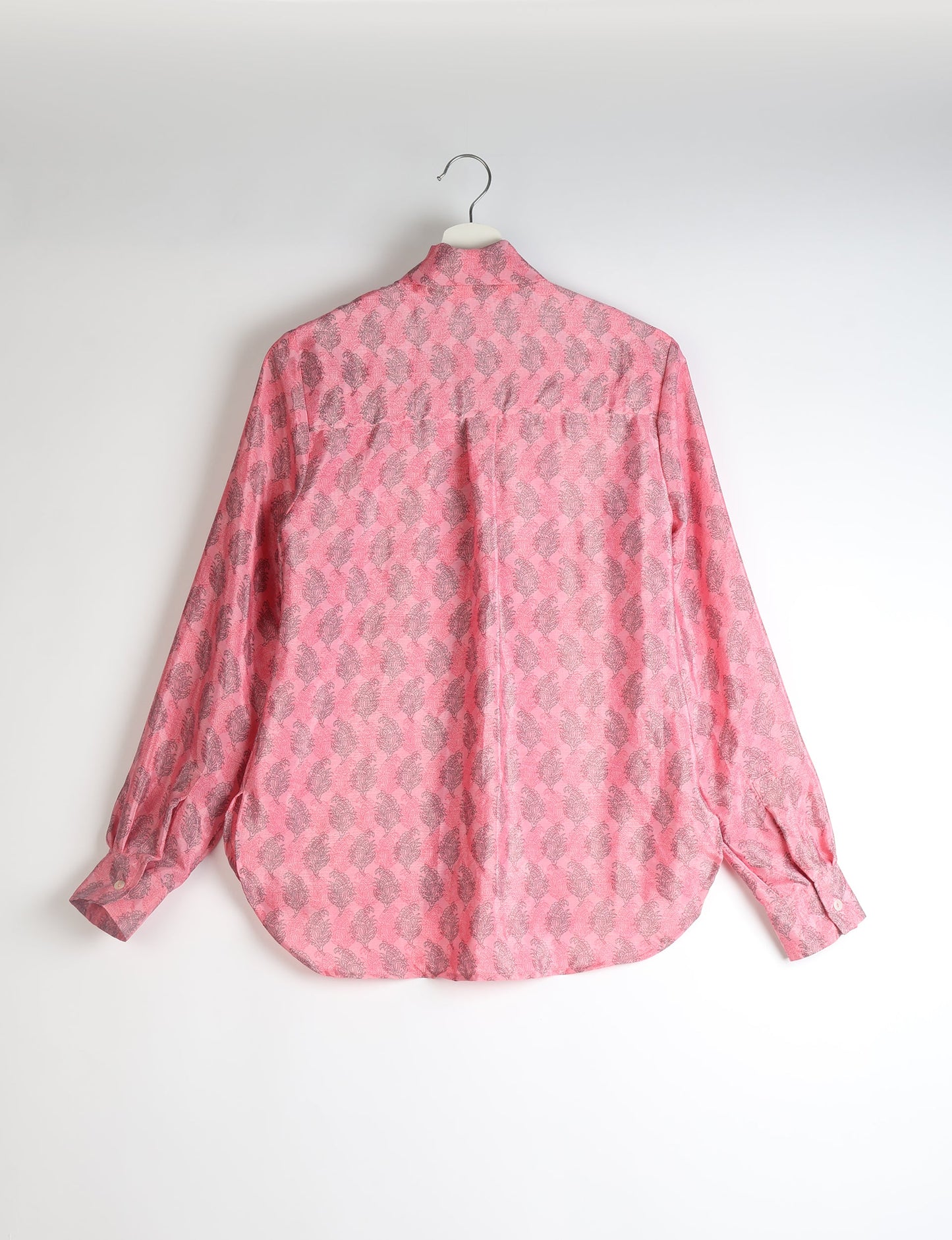 Pink long-sleeve shirt with gray leaf pattern, buttoned cuffs, and back pleat, hanging on white hanger, back view