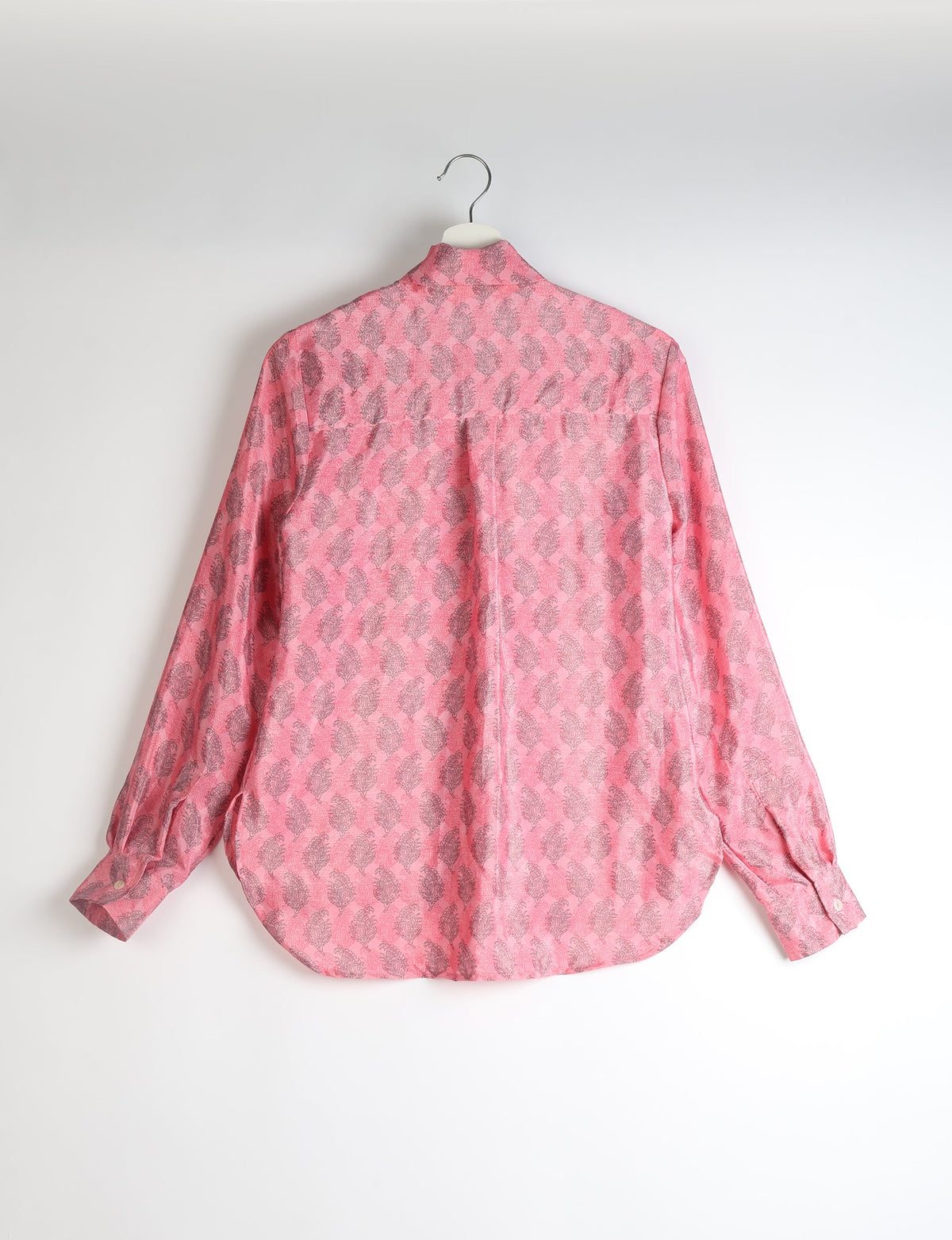 Pink long-sleeve shirt with gray leaf pattern, buttoned cuffs, and back pleat, hanging on white hanger, back view