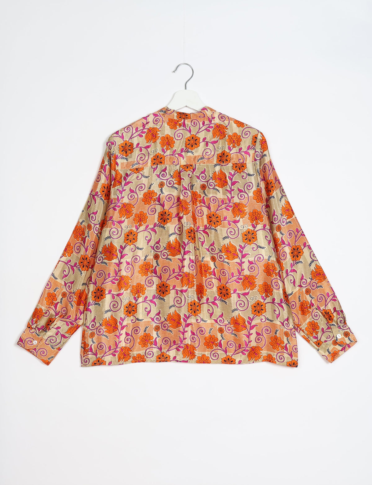Long-sleeve blouse with orange floral and purple vine print on beige checkered background, shown from back on white hanger