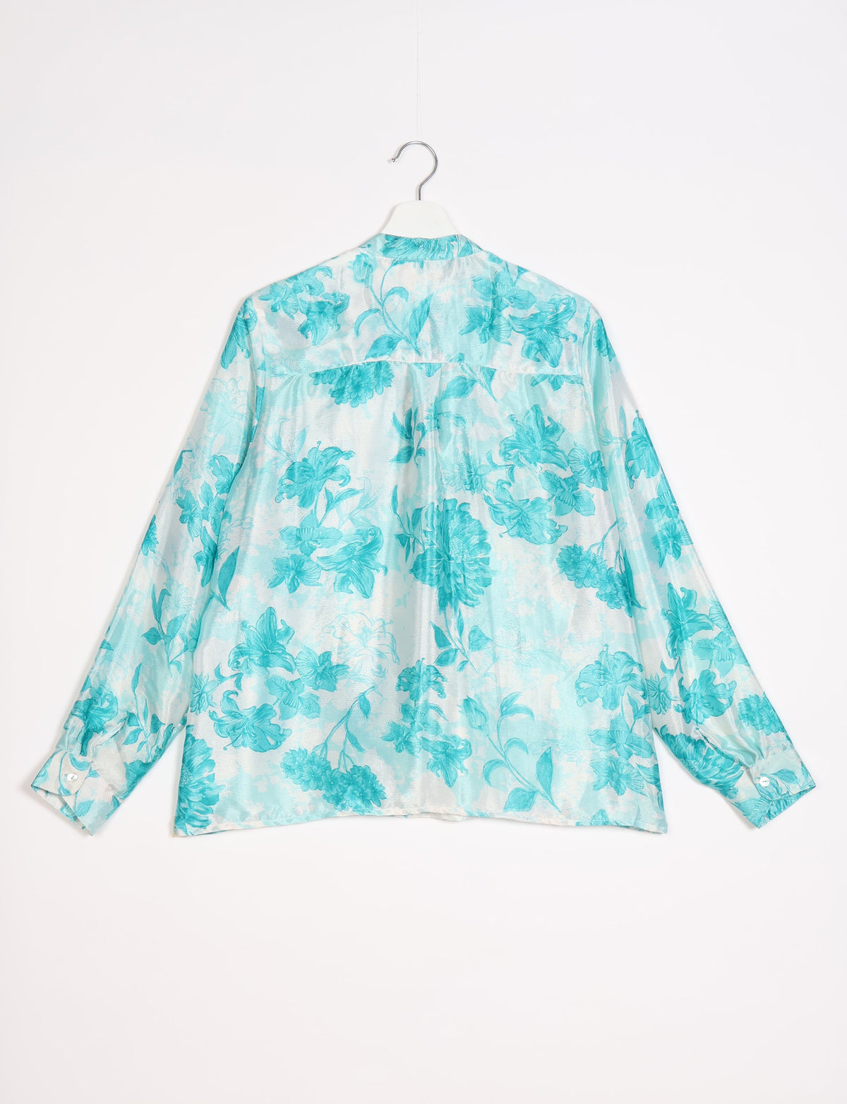 Blue floral patterned long-sleeve blouse with buttoned cuffs hanging on white hanger, back view on white background