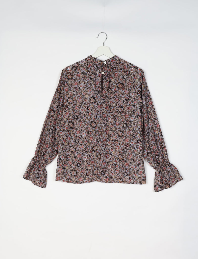 Black blouse with multicolor floral print, long sleeves with ruffle cuffs, and back button closure, hanging on white hanger