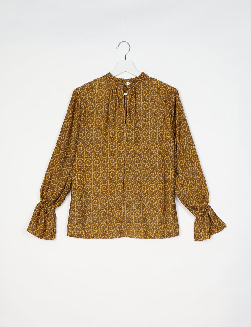 Yellow abstract patterned flowing blouse with long sleeves and button closure at the back, shown on hanger