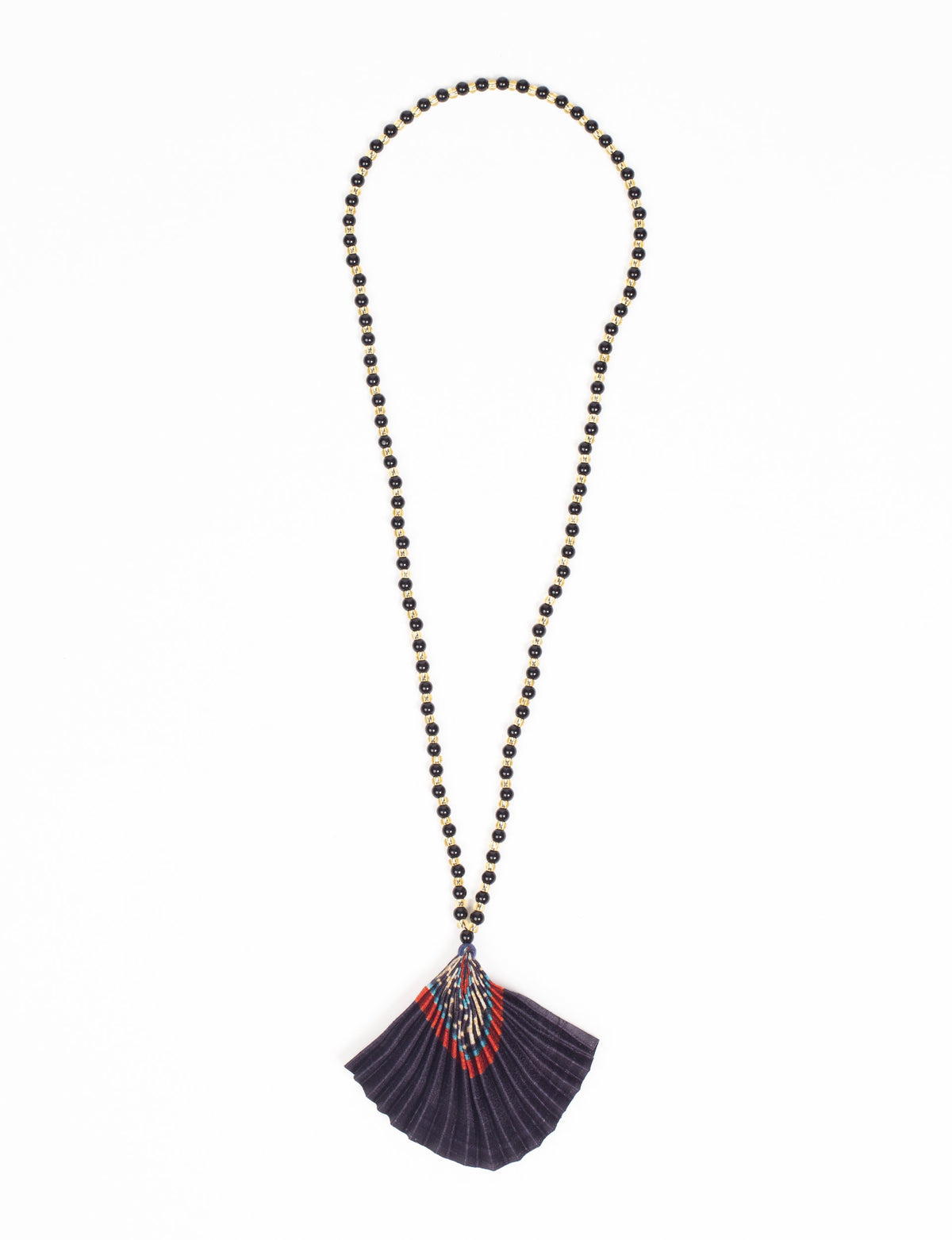 Necklace with black and gold beads and a pleated fabric pendant in blue, red, and beige abstract pattern, flat lay view