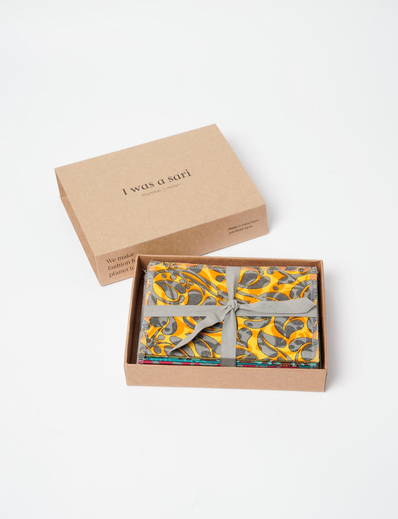 Folded postcard set with upcycled yellow and gray sari fabric tied with gray ribbon in a brown box labeled I was a sari