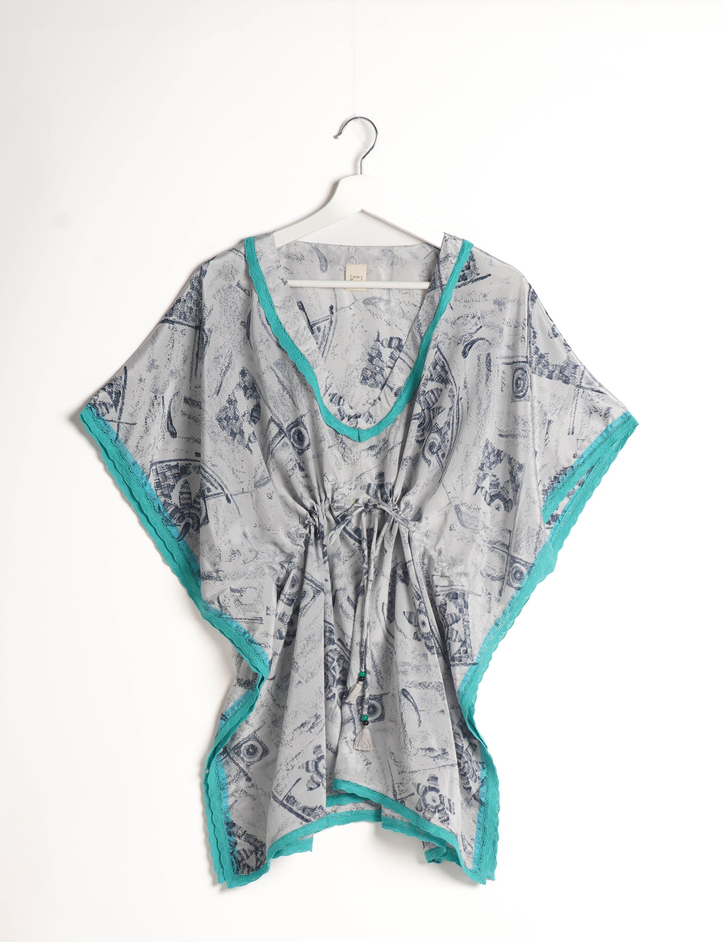 Elevate your style with our short kaftan, a perfect blend of ethical and green fashion. The light and loose-flowing fabric, drawstring waist, beaded tassel ends, and delicate lace edging make it a versatile choice for urban summers, beachwear, or poolside elegance. Enjoy sustainable and fashionable living.