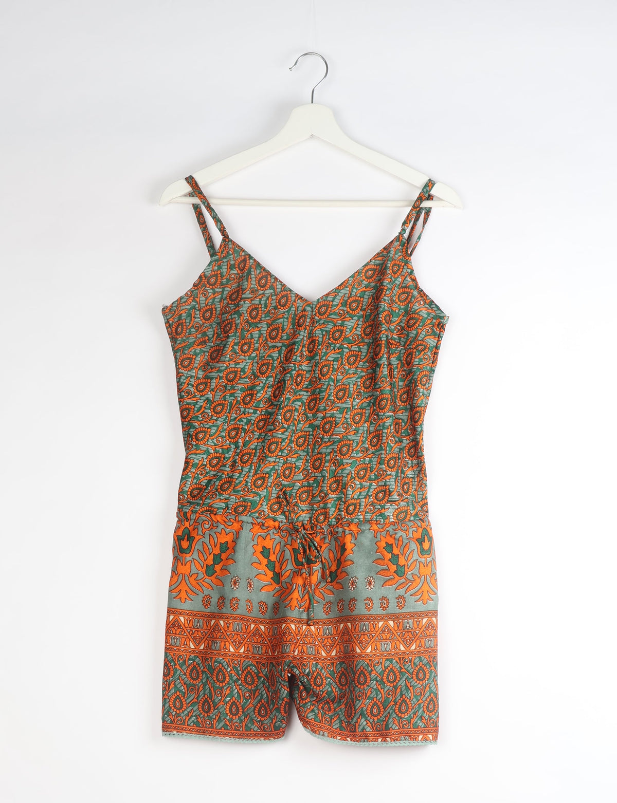 Orange paisley playsuit with double straps and drawstring waist, hanging on a white hanger against a white background