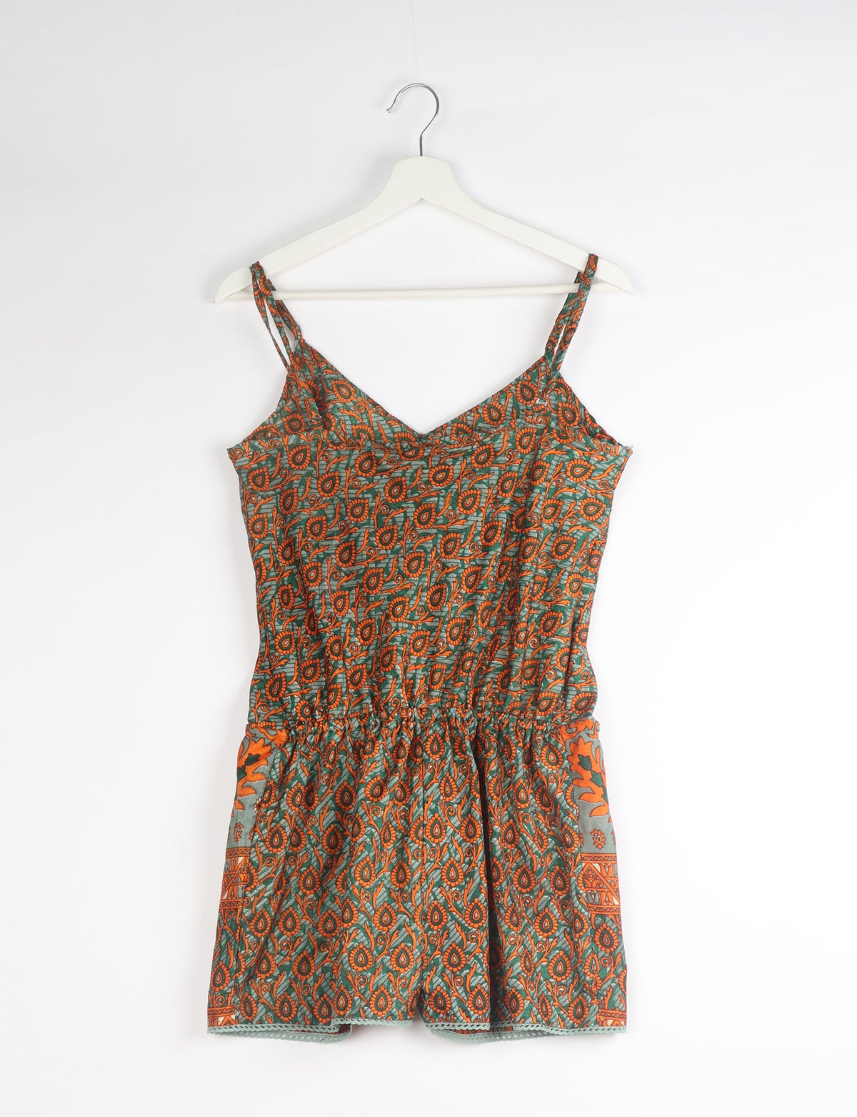 Orange paisley patterned playsuit with lace trim, adjustable straps, and elastic waist, hanging on white hanger front view