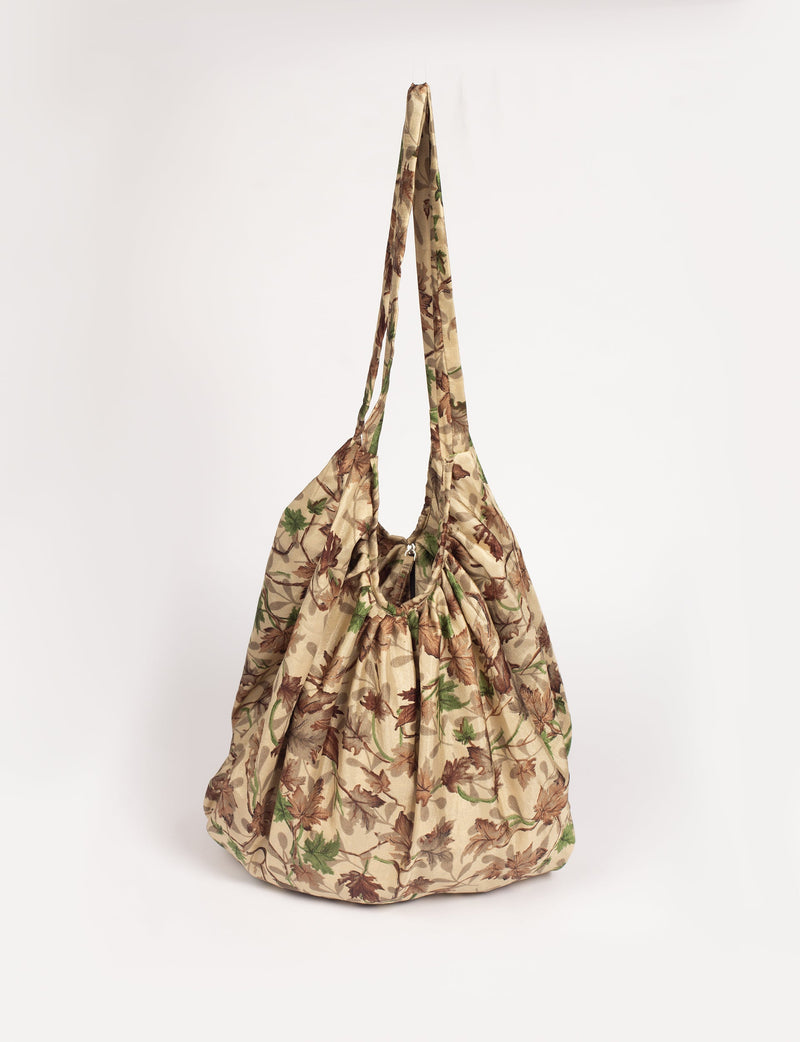 Beige tropical print hobo bag with gathered top and long shoulder straps, front view hanging against white background