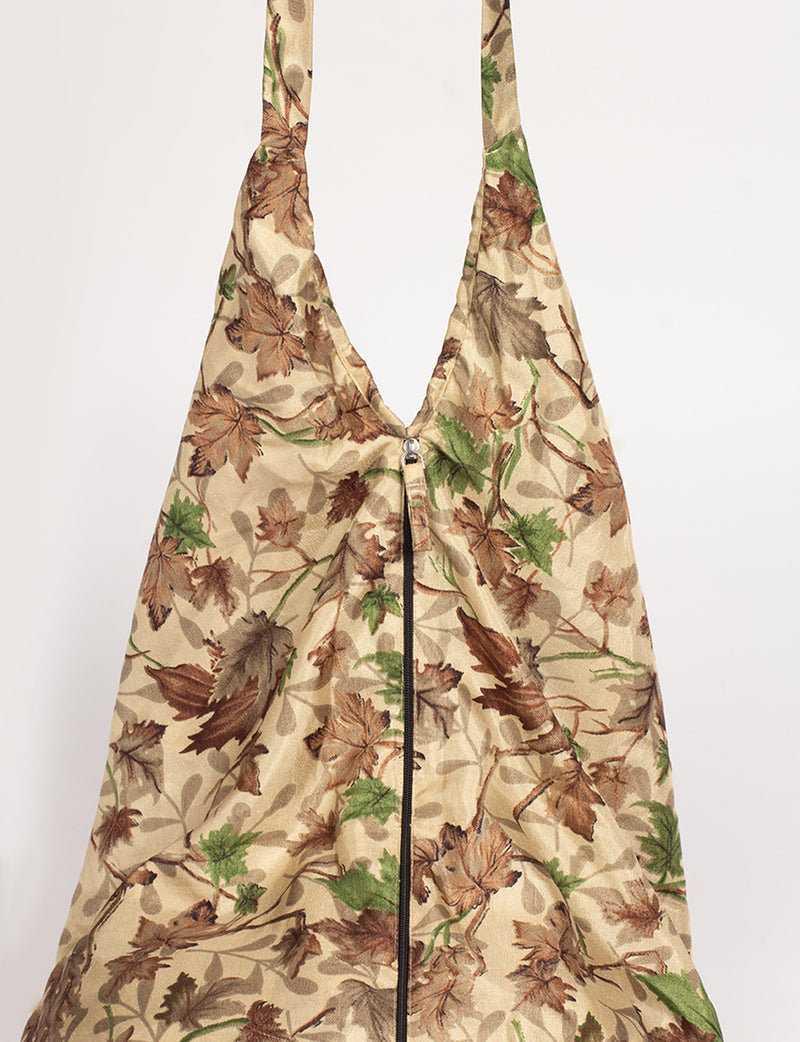 Beige hobo bag with tropical leaf print in brown and green, front view, featuring a central zipper closure