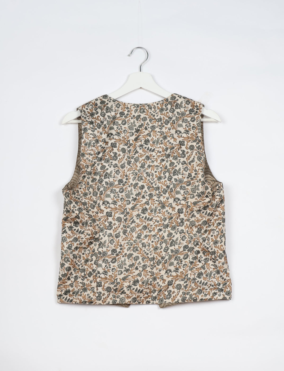 White tropical sleeveless waistcoat with brown and gray floral print, shown from back on white hanger against white background