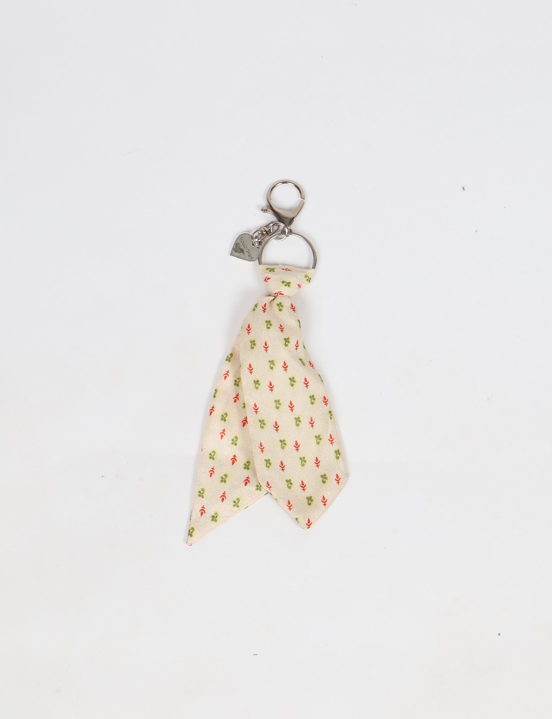 Beige fabric tie keychain with small red and green floral micro design and silver metal clasp with heart charm