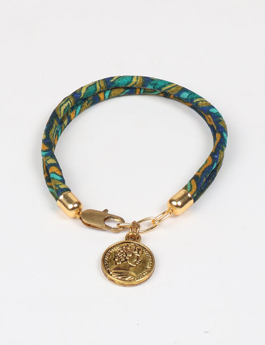 A close-up image of a hand wearing the Sari Rope Bracelete with Charm, showcasing its colorful threads and unique design. This accessory embodies ethical fashion and sustainability, crafted from repurposed saris for a stylish and eco-conscious statement.