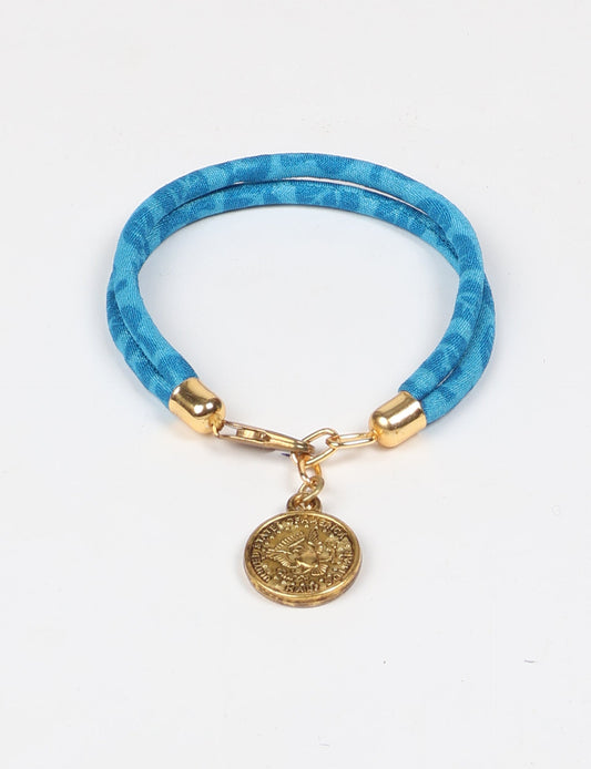 A close-up image of a hand wearing the Sari Rope Bracelete with Charm, showcasing its colorful threads and unique design. This accessory embodies ethical fashion and sustainability, crafted from repurposed saris for a stylish and eco-conscious statement.