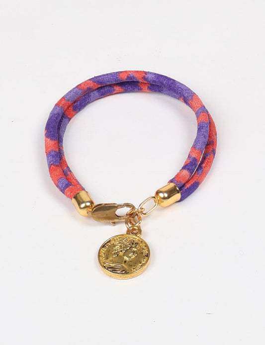A close-up image of a hand wearing the Sari Rope Bracelete with Charm, showcasing its colorful threads and unique design. This accessory embodies ethical fashion and sustainability, crafted from repurposed saris for a stylish and eco-conscious statement.