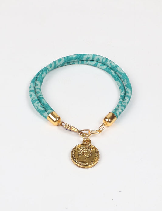 A close-up image of a hand wearing the Sari Rope Bracelete with Charm, showcasing its colorful threads and unique design. This accessory embodies ethical fashion and sustainability, crafted from repurposed saris for a stylish and eco-conscious statement.