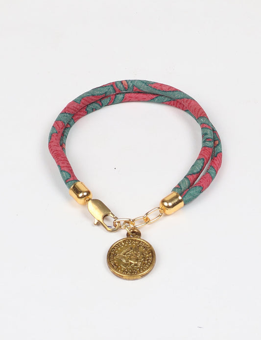 A close-up image of a hand wearing the Sari Rope Bracelete with Charm, showcasing its colorful threads and unique design. This accessory embodies ethical fashion and sustainability, crafted from repurposed saris for a stylish and eco-conscious statement.