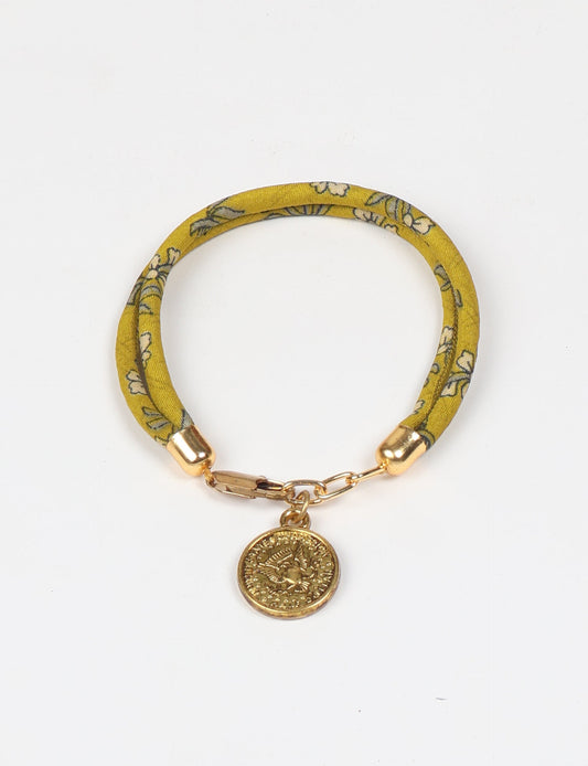 A close-up image of a hand wearing the Sari Rope Bracelete with Charm, showcasing its colorful threads and unique design. This accessory embodies ethical fashion and sustainability, crafted from repurposed saris for a stylish and eco-conscious statement.