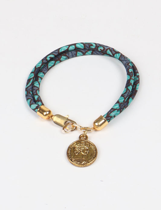 A close-up image of a hand wearing the Sari Rope Bracelete with Charm, showcasing its colorful threads and unique design. This accessory embodies ethical fashion and sustainability, crafted from repurposed saris for a stylish and eco-conscious statement.