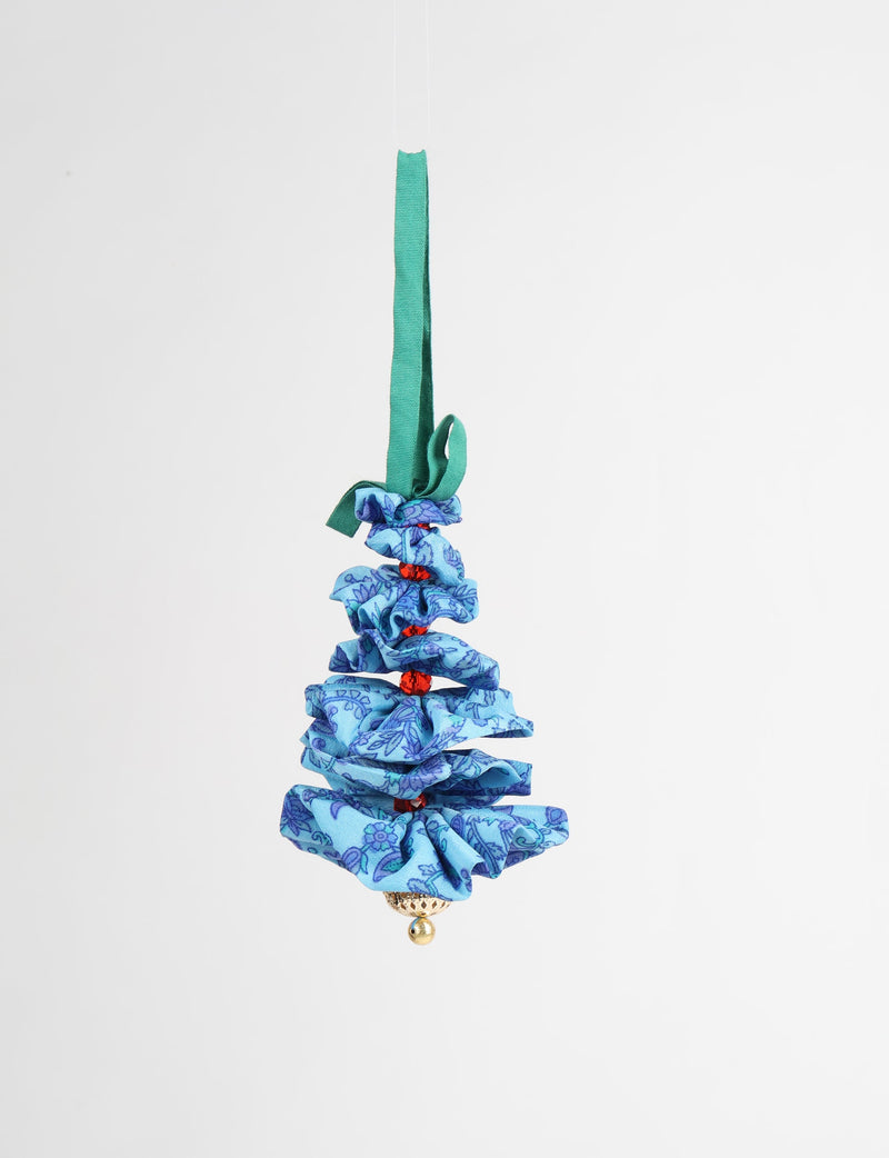 Blue fabric Christmas tree ornament with abstract floral pattern, red beads, gold bell, and green hanging loop, front view