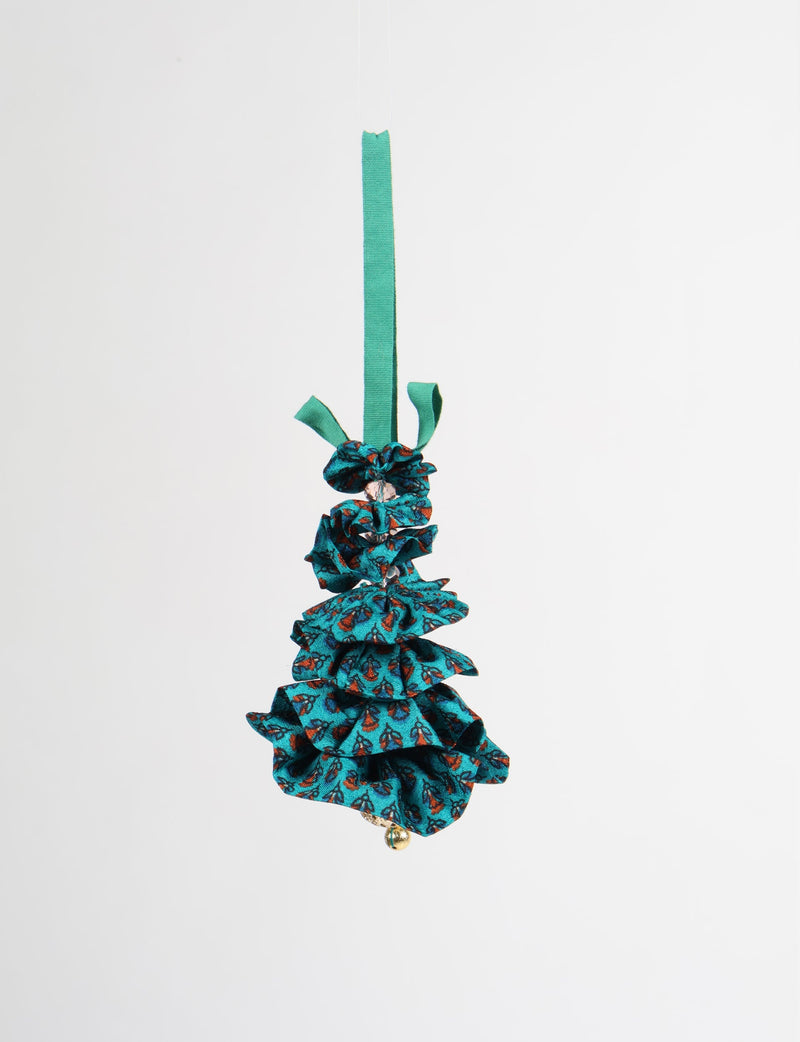 Blue fabric Christmas tree ornament with abstract orange and black pattern, green hanging loop, and small gold bell at bottom