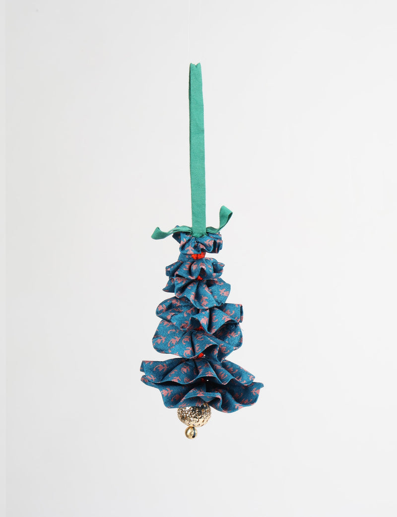 Blue fabric Christmas tree ornament with pink abstract pattern, green hanging loop, and gold textured bell at bottom