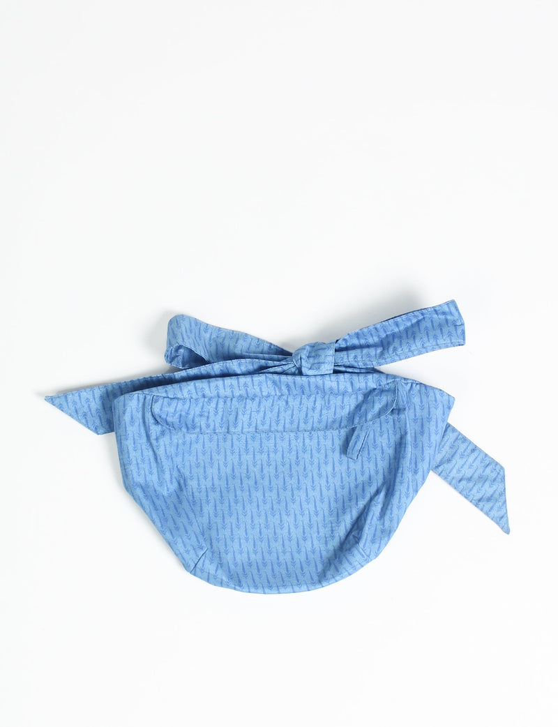 Blue midi belt bag with micro arrow pattern, front pocket, and tied adjustable strap, flat lay on white background