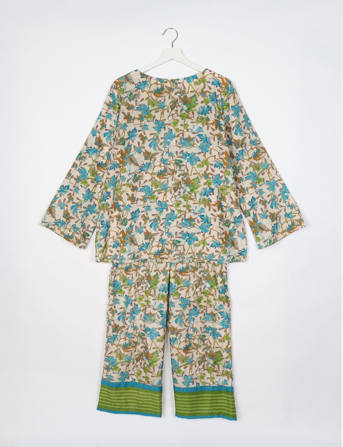 Beige lounge set with long sleeves and pants featuring blue, green, and brown leaf print and green striped cuffs, shown flat