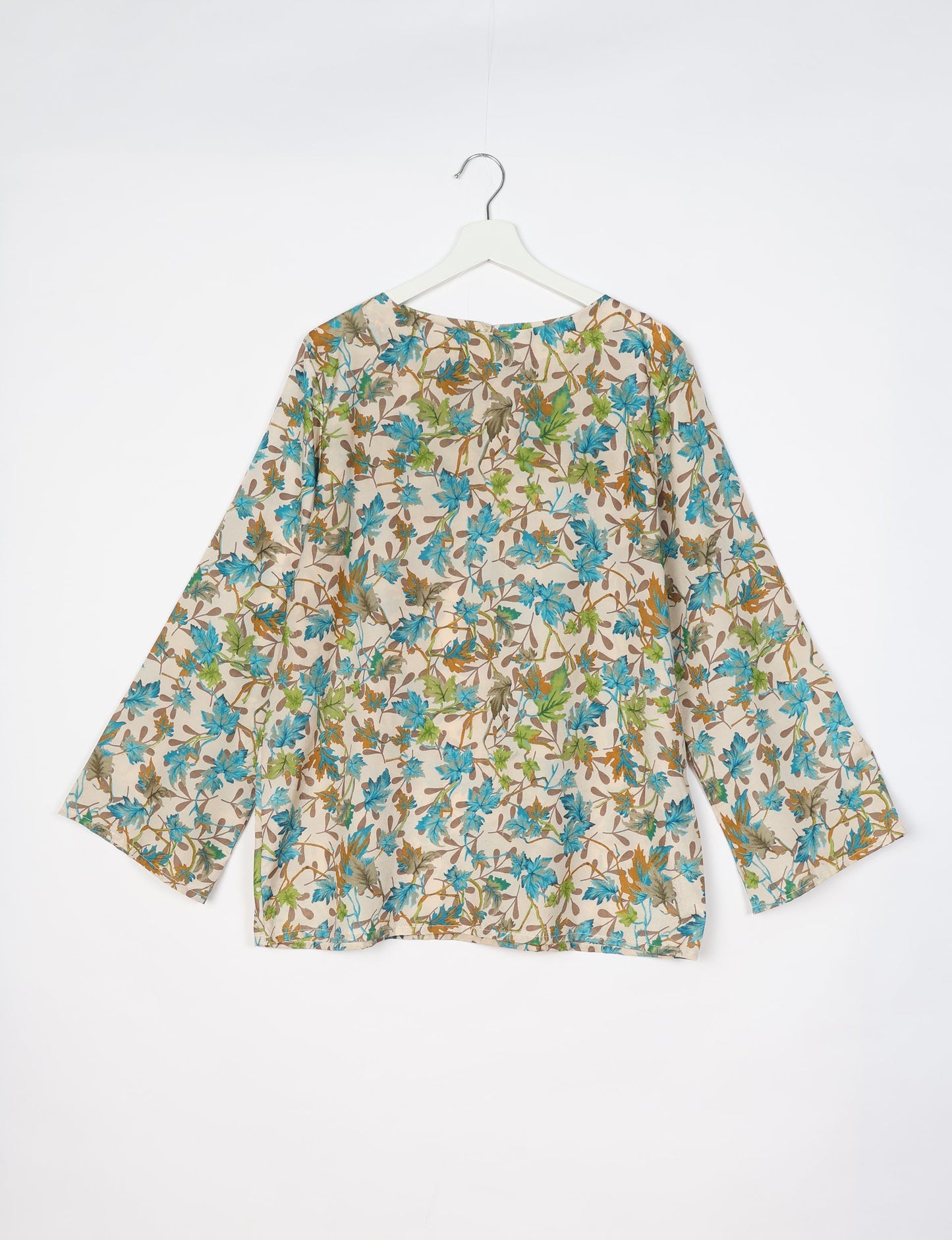 Beige lounge top with blue, green, and brown leaf print, long sleeves, and round neckline, shown from back on white hanger