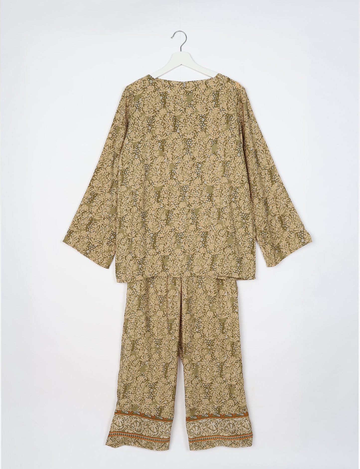 Beige tropical print lounge set with long sleeves, round neckline, and wide-leg pants with patterned cuffs, hanging on white