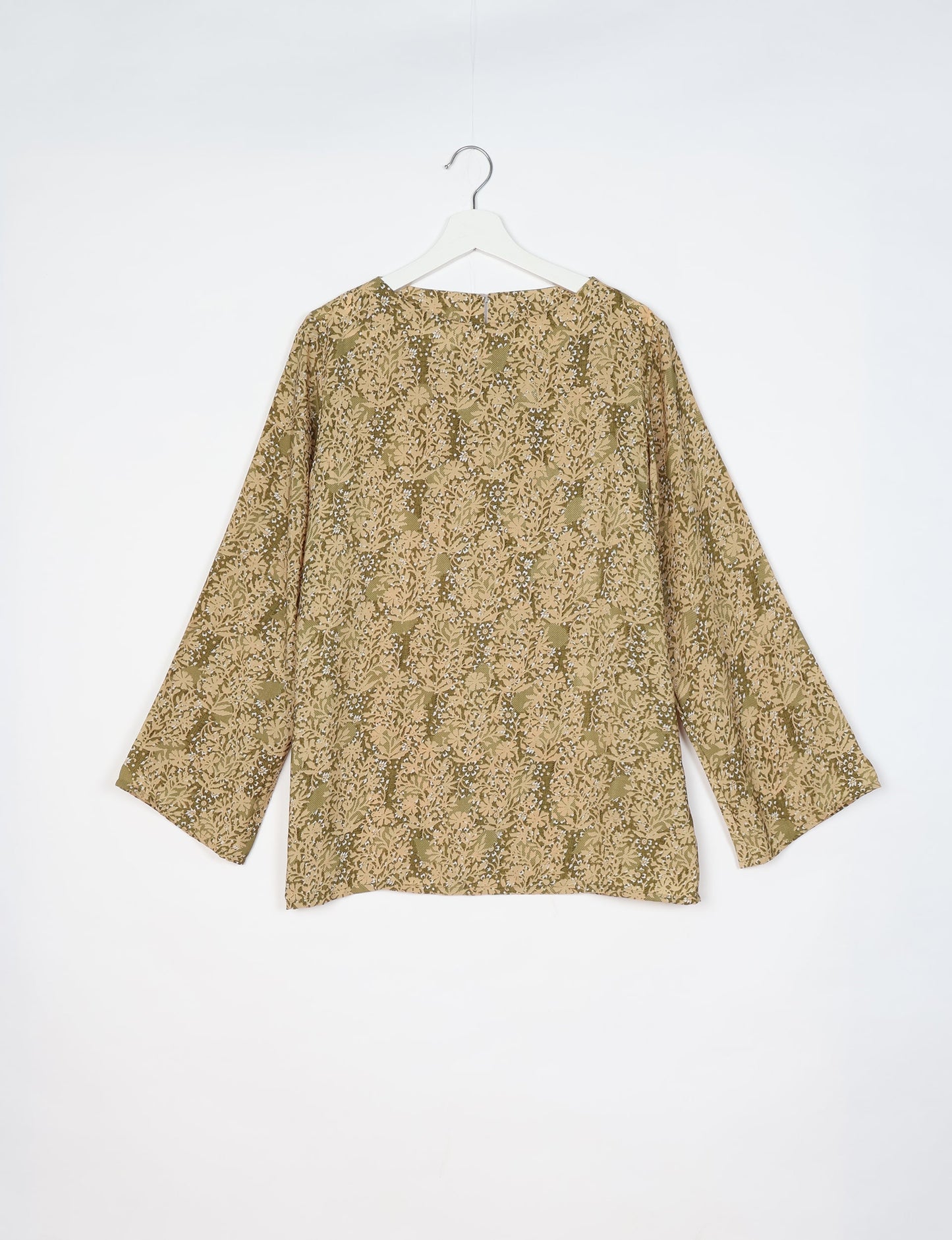 Beige long-sleeve lounge top with tropical floral pattern hanging on white hanger against white background